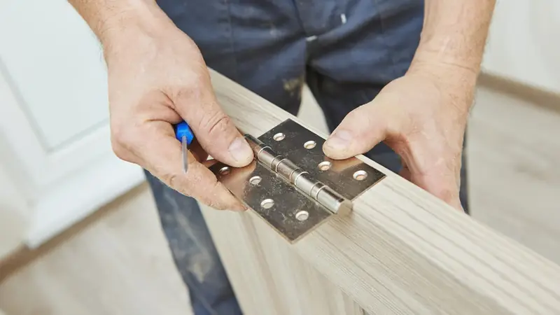 Hands fitting a door hinge