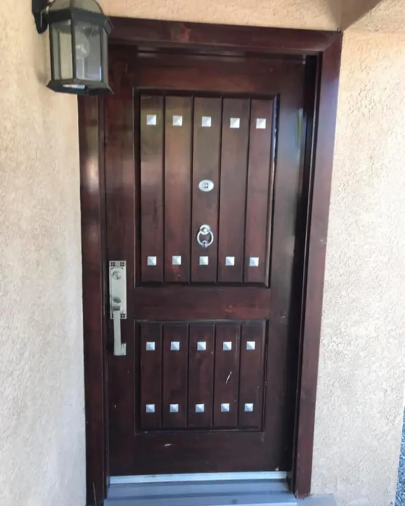 Dark-stained decorative entry door with speakeasy grilles, installed in Albuquerque